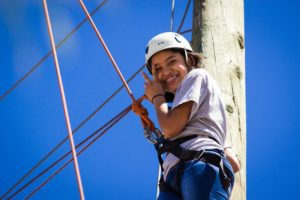 Girl smiles while attached to rope in climbing gear
