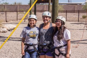 Three girls smile for picture with climbing gear