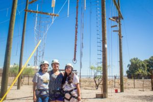 Three girls smile for picture with climbing gear