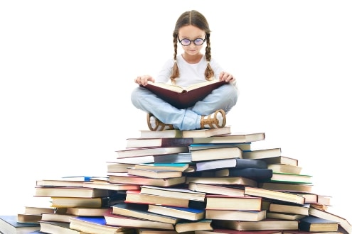 Girl reading a book while sitting on a pile of books