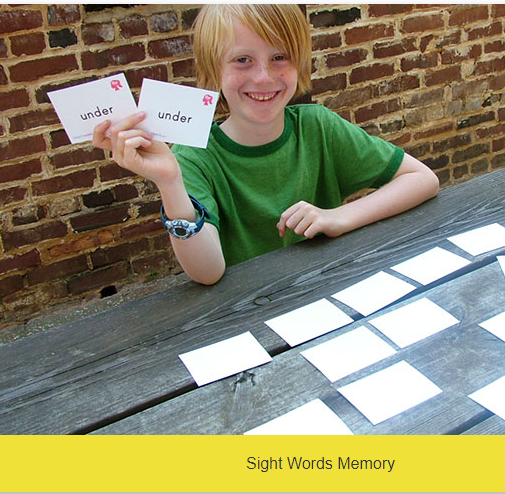 Child holding up two cards with the same word on each card.