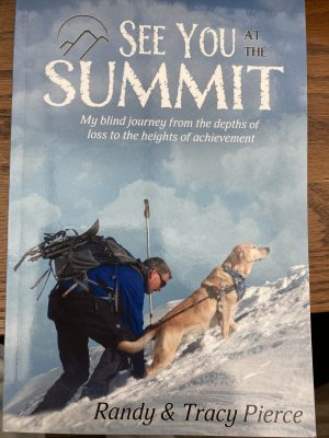 Book cover of a man climbing a snowy mountain with his guide dog.