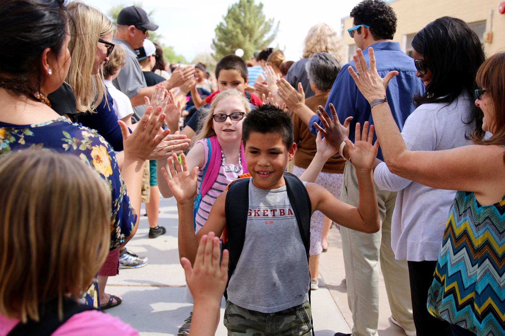 PDSD bus farewell with students giving high-fives to teachers and staff.