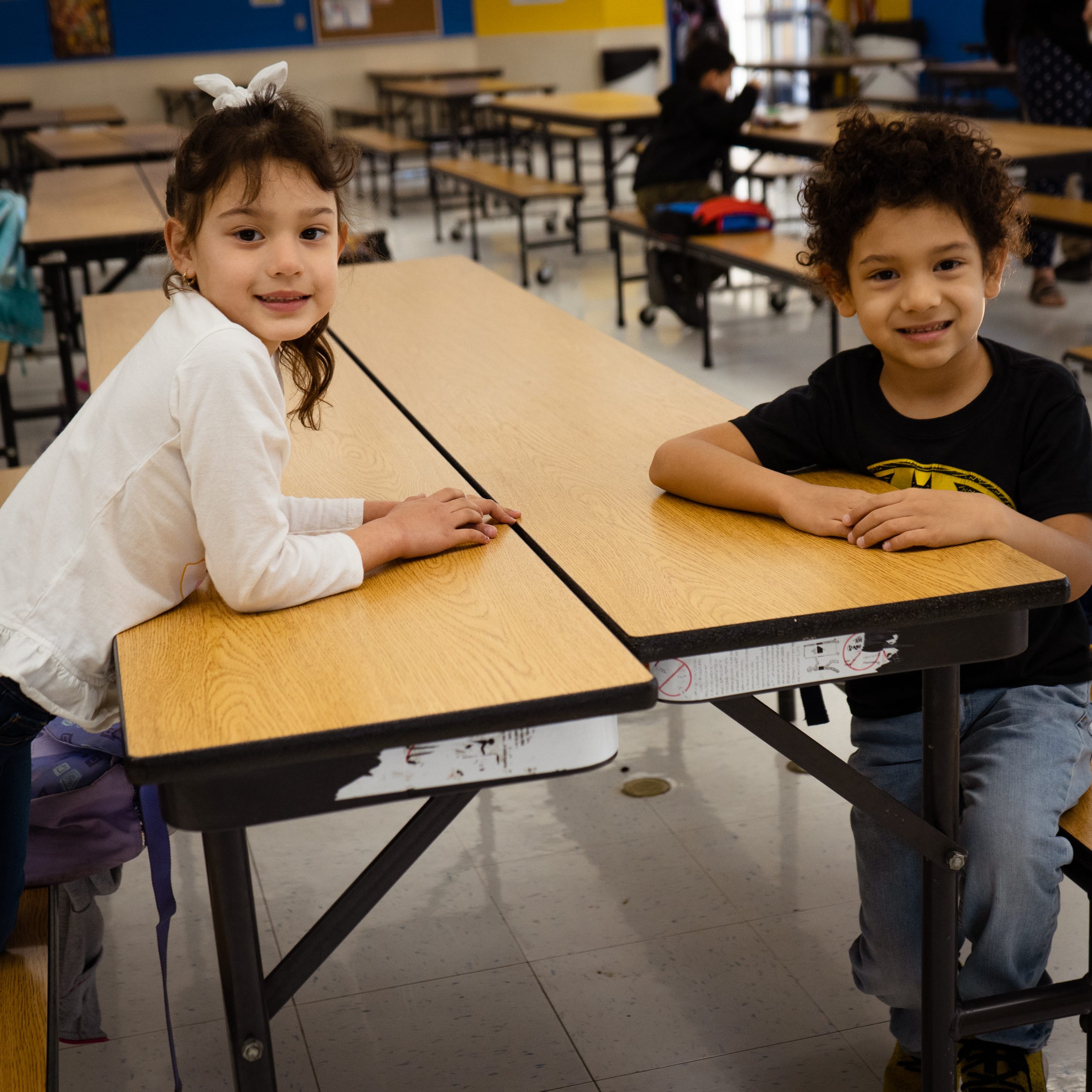Two students are sitting at a table and smiling for a photo