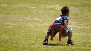 A little boy prepares to run during flag football.