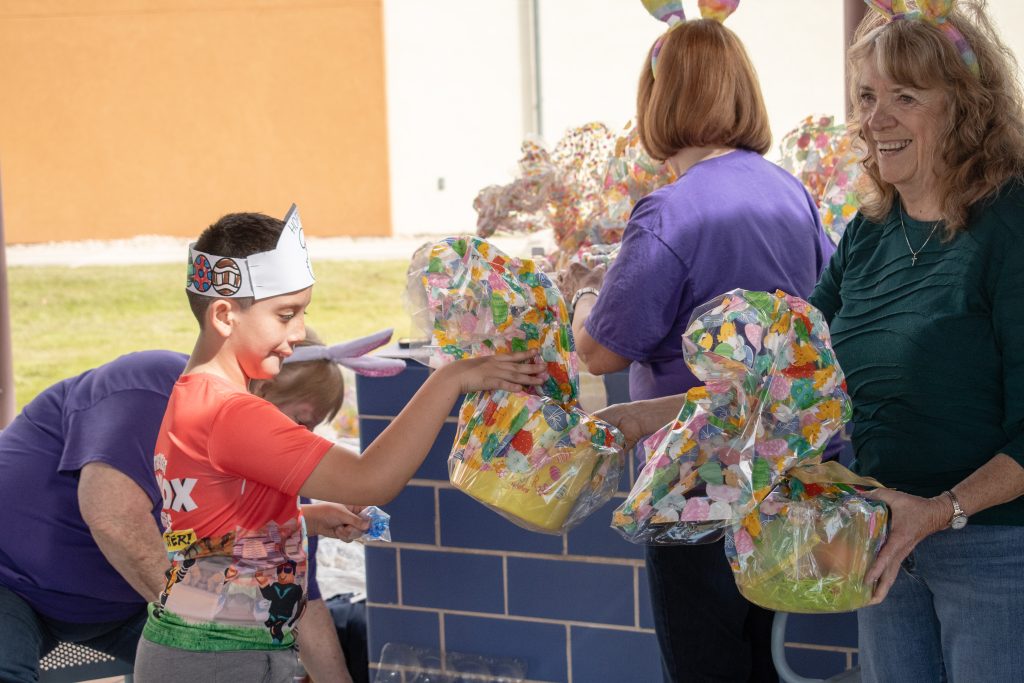 a student in an easter crown picks out their easter basket from the volunteers