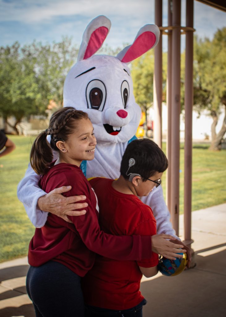 The easter bunny hugs two students