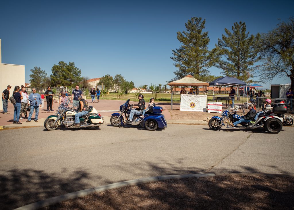 a photo showing 3 motorcycles, the students getting on to ride in front of the gym.
