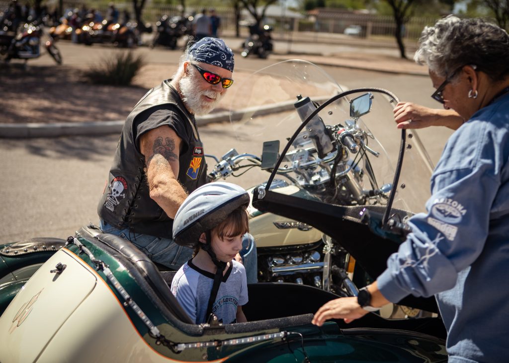 The small student is back from the ride, all smiles. The biker gives them a fist bump.