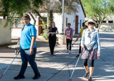 A photo of multiple visually impaired students and staff walking across ASDB campus. Each of them is using a white cane to help themselves navigate.