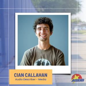 A portrait photo of Audio Describer Cian Callahan. Cian has short curly hair and is wearing an army green t-shirt displaying the band U2.
